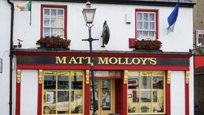 En pub kaldet 'Matt Molloy's' med en facade i rødt og hvidt, store vinduer og en sort lygtepæl foran.