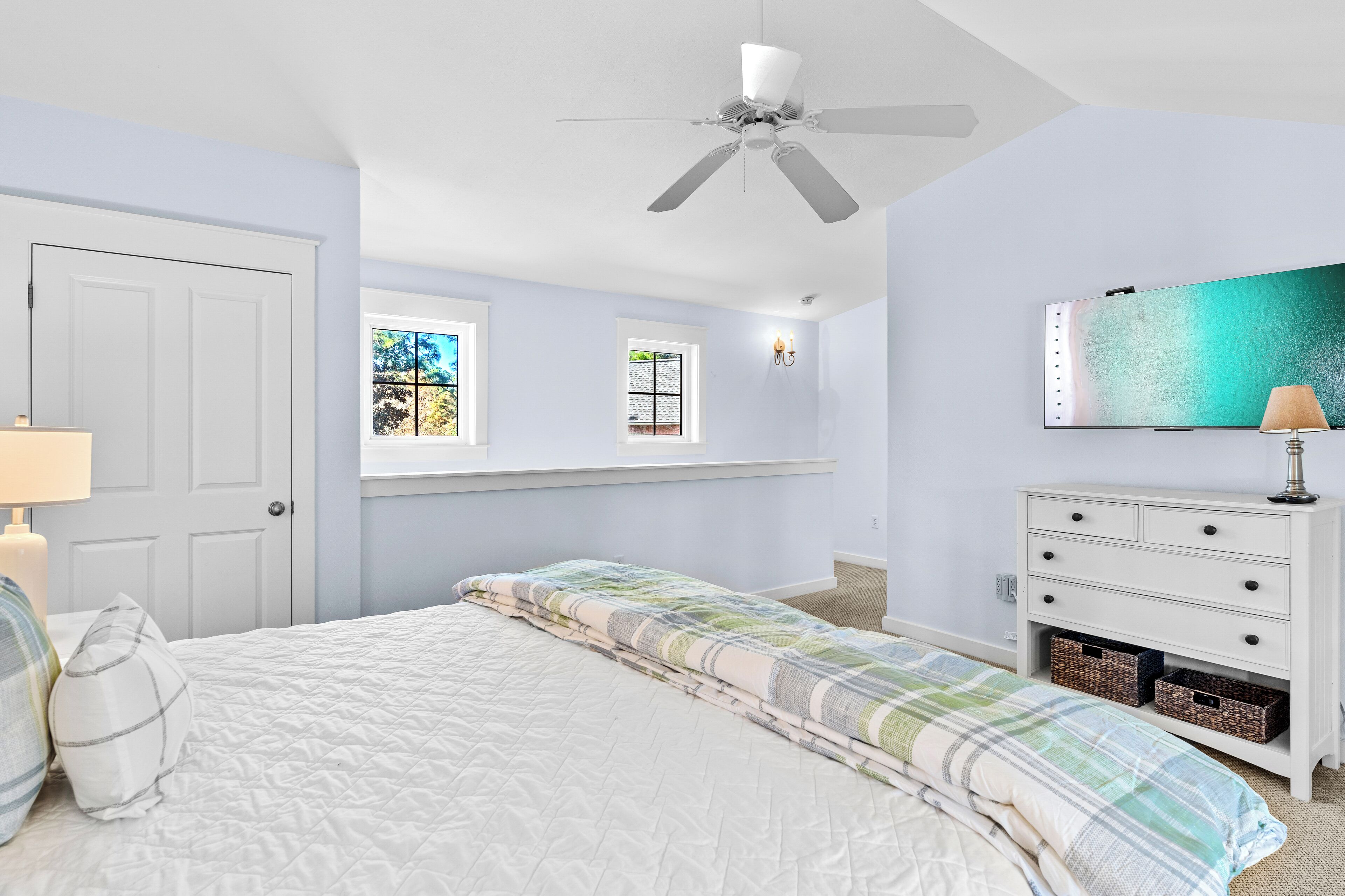 A bedroom with a bed, a dresser, a ceiling fan, and a window.