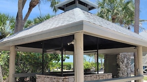 A covered outdoor area with a stone base, benches, and palm trees in the background. - Luxury Condo on Little Gasparilla Island-Family Friendly, ferry included (Placida)