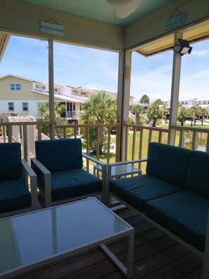 Un espacio de estar al aire libre cubierto con una mesa y dos sofás, un letrero que dice 'BEACH HOUSE' y un letrero que indica 'SOLO Mareas Buenas'.