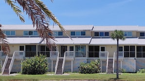A multi-story hotel with balconies, a pool, and palm trees. - Luxury Condo on Little Gasparilla Island-Family Friendly, ferry included (Placida)