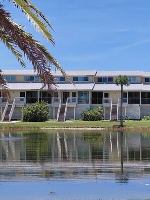 A multi-story hotel with balconies, a pool, and palm trees.