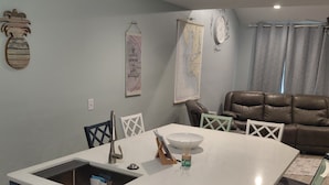 A kitchen with a central island, a built-in dishwasher, and a dining area with chairs and a table. - Luxury Condo on Little Gasparilla Island-Family Friendly, ferry included (Placida)