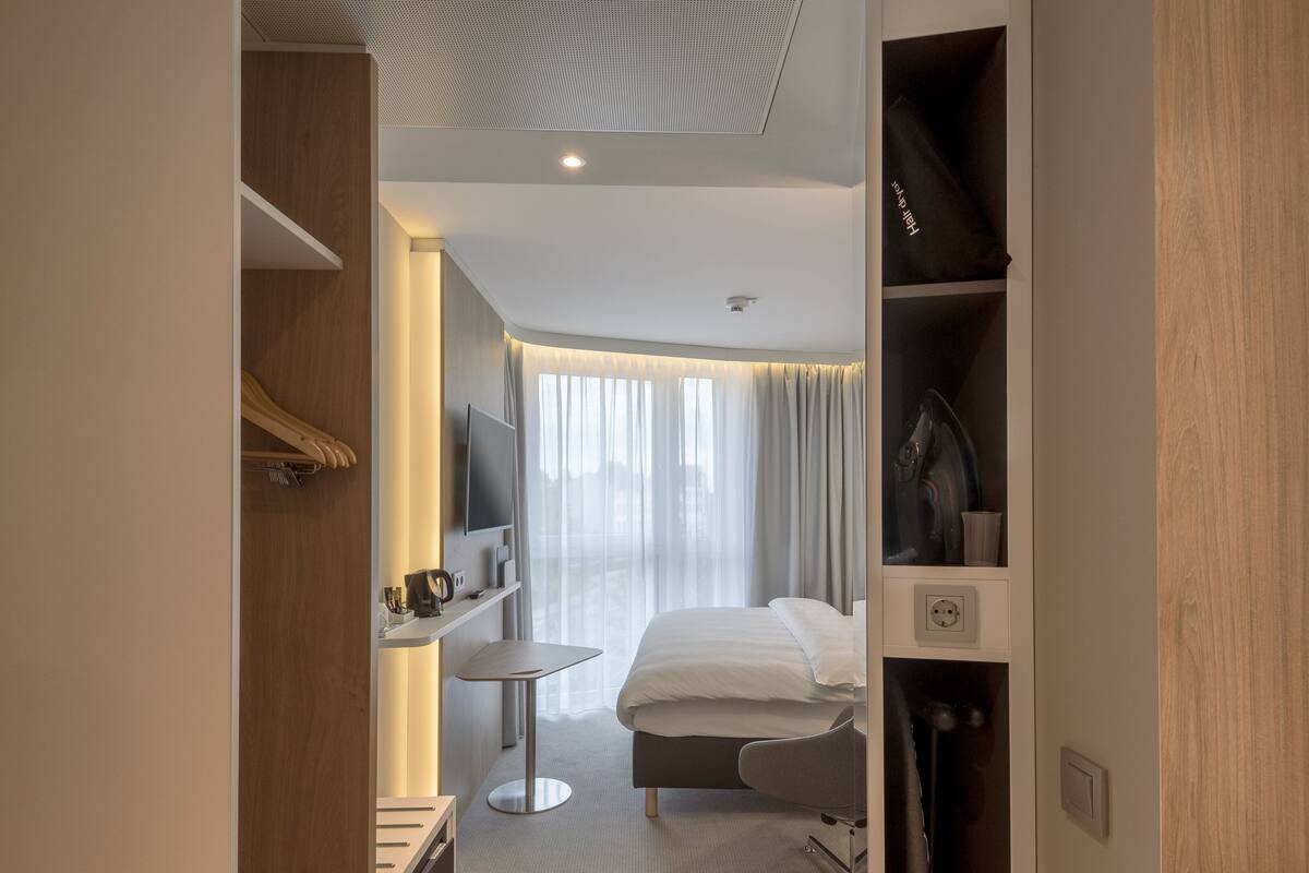 A modern hotel room with a bed, bedside table, and a TV.
