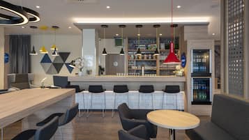 A modern bar area with a long counter, multiple bar stools, and a seating area with round tables and chairs.