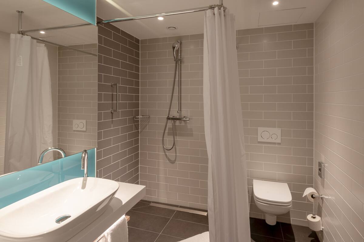 A modern bathroom with a glass-enclosed shower, a white sink, and a toilet.
