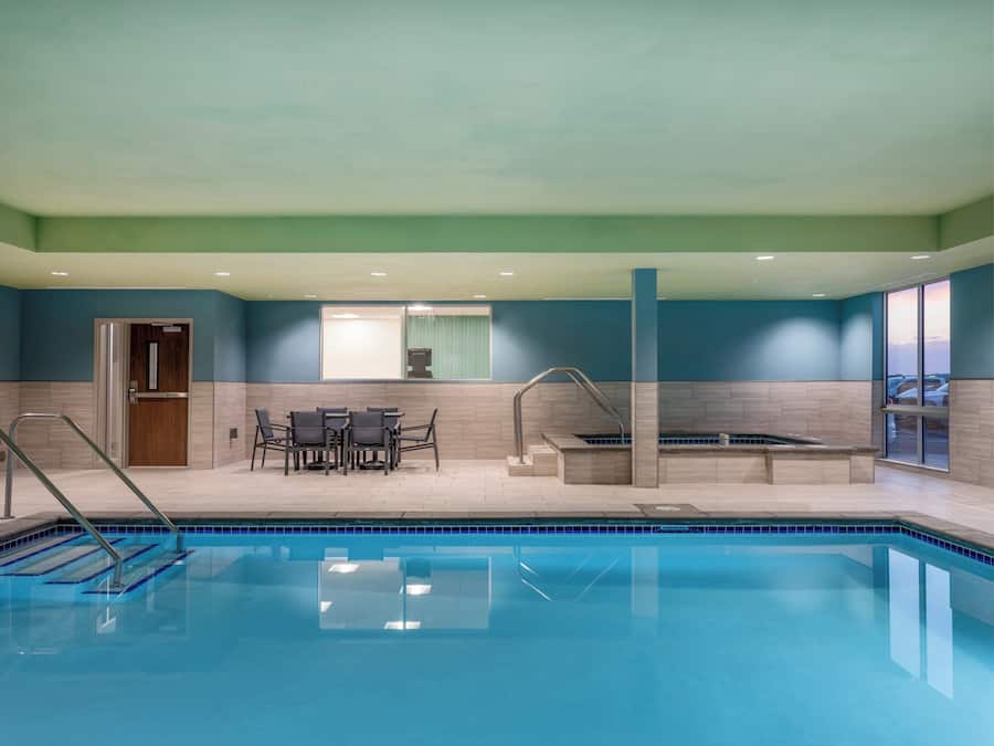 A swimming pool with a sun terrace, a seating area, and a door.