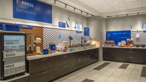 A breakfast area with a yogurt machine, cereal, and hot food options. - Holiday Inn Express & Suites Watertown by IHG (Watertown)
