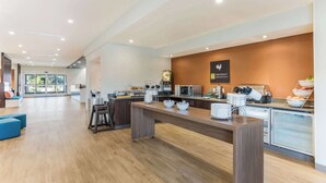 Un área de cocina moderna con una encimera larga, varios electrodomésticos y un cartel que dice 'MainStart Breakfast'.