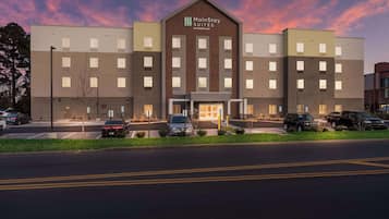 A MainStay Suites Extended Stay hotel with a modern design, multiple parking spaces, and a well-lit entrance.