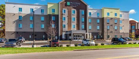 Un hôtel MainStay Suites Extended Stay au design moderne, avec plusieurs étages et un parking situé à l’avant.