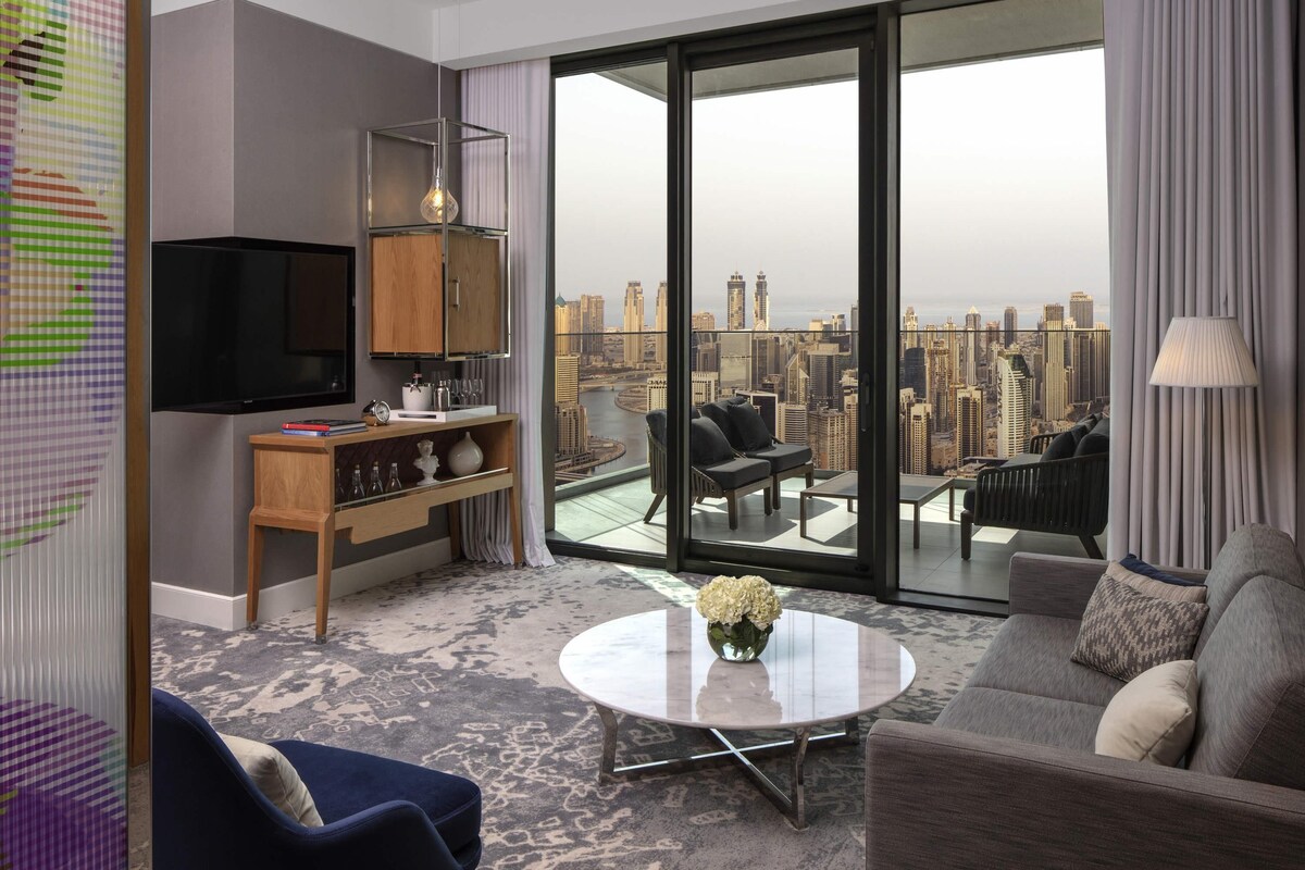 A modern living room with a city view, a flat-screen TV, a coffee table, and a sofa.