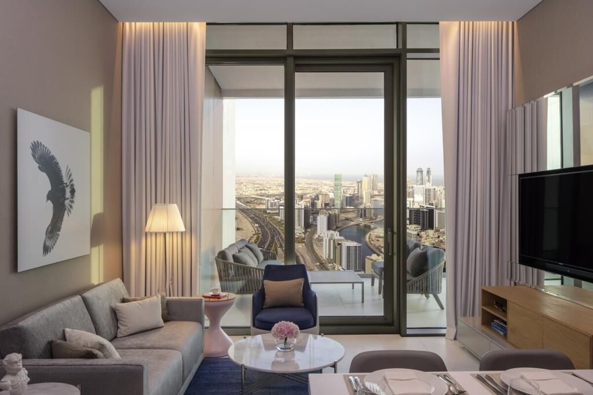 A modern living room with a city view, a sofa, a coffee table, and a television.