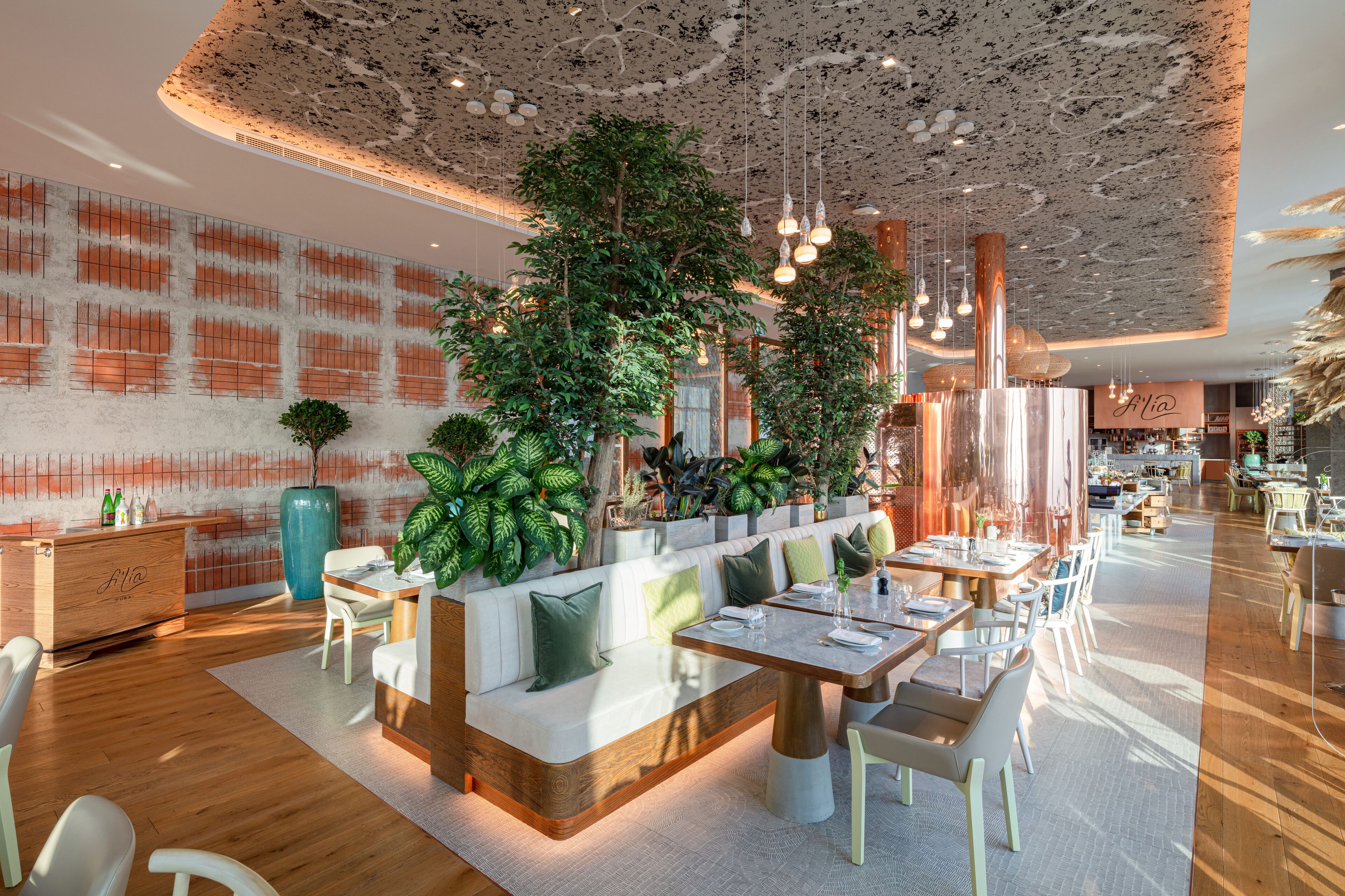 Un restaurant moderne doté d’un espace de restauration central, de tables en bois et d’un plafond orné de luminaires suspendus.