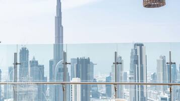 A dining area with a city view, featuring a round table with chairs and a glass railing.