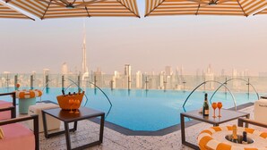 A rooftop pool area with lounge chairs, umbrellas, and a city skyline view. - SLS Dubai Hotel & Residences (Dubai)