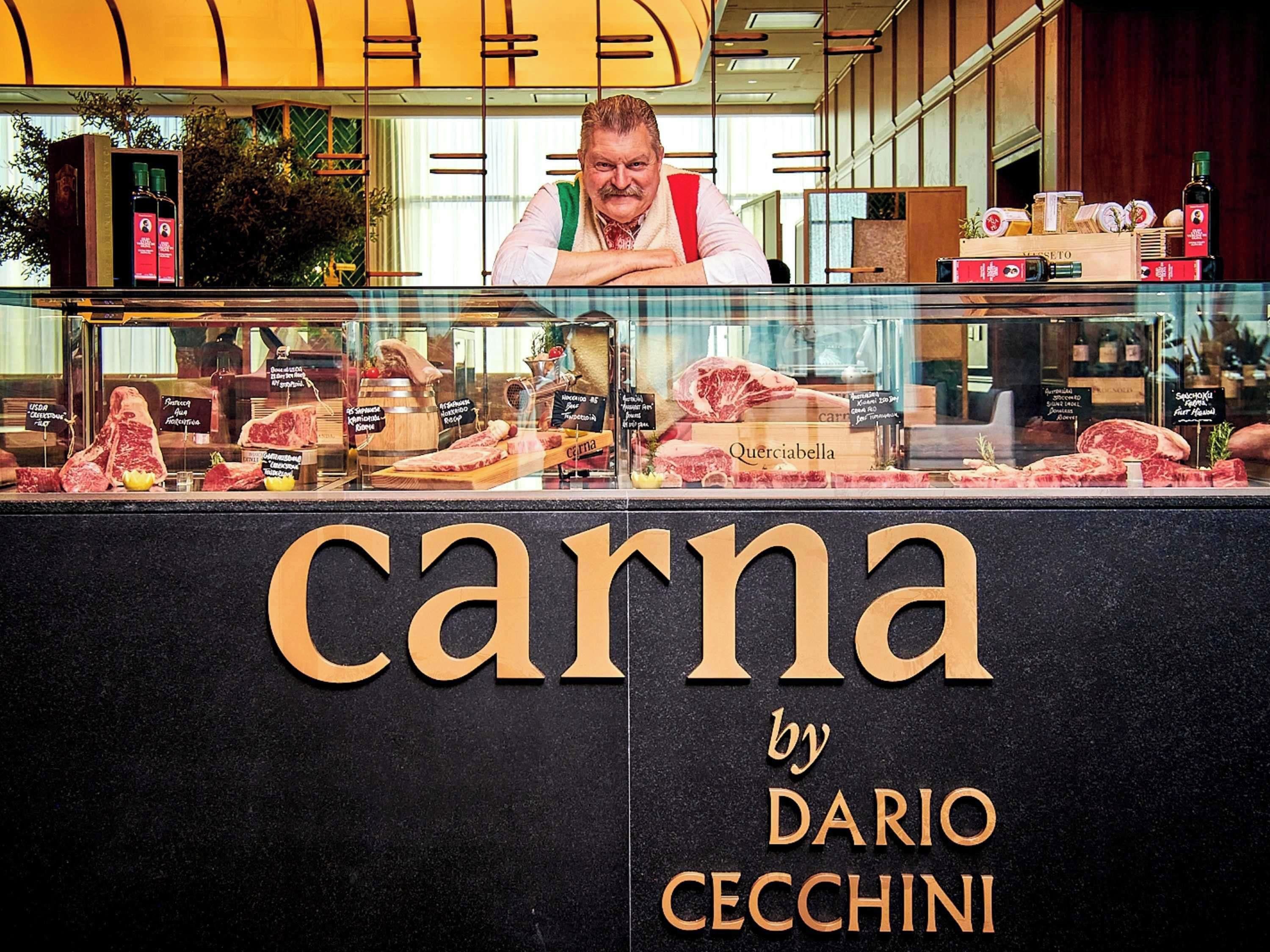 A butcher shop with a display of various meats and a sign that reads 'carna by Dario CECCHINI'.