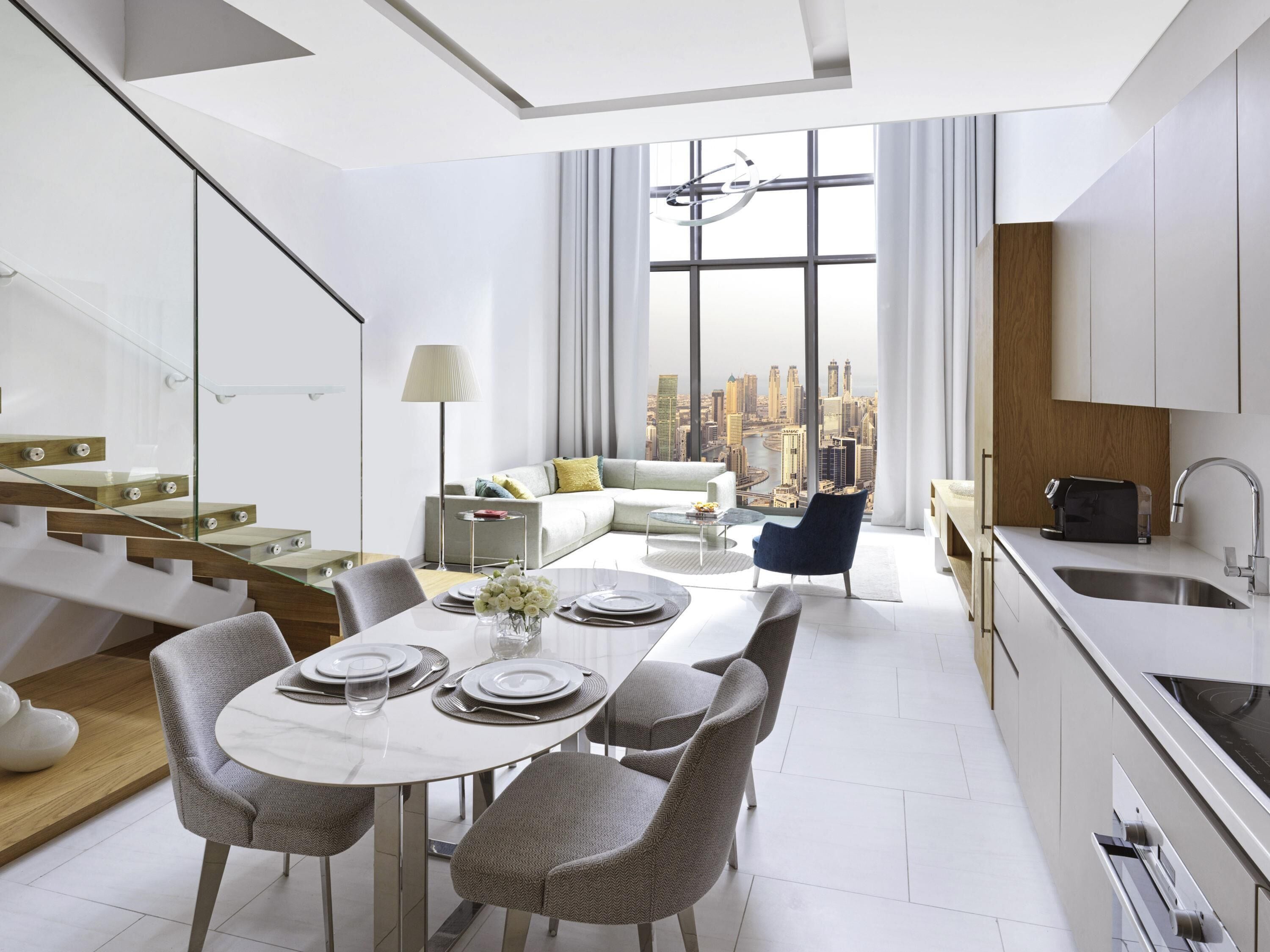 A modern apartment with a dining area, kitchen, and a city view.