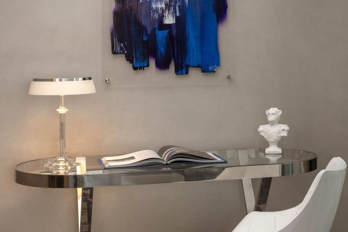 A modern room with a glass table, a white bust, and a book.