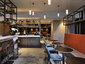 A modern bar area with seating, a counter, and hanging pendant lights.