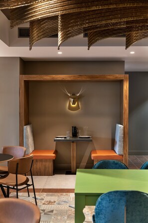A modern dining area with a wooden partition, a table with chairs, and a unique wall-mounted light fixture. - Mercure Auckland Queen Street (Auckland)
