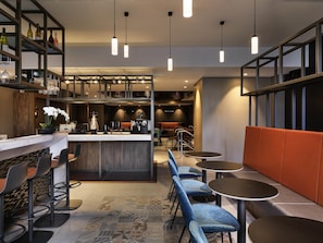 Un espacio moderno de bar con asientos, una barra y luminarias colgantes.