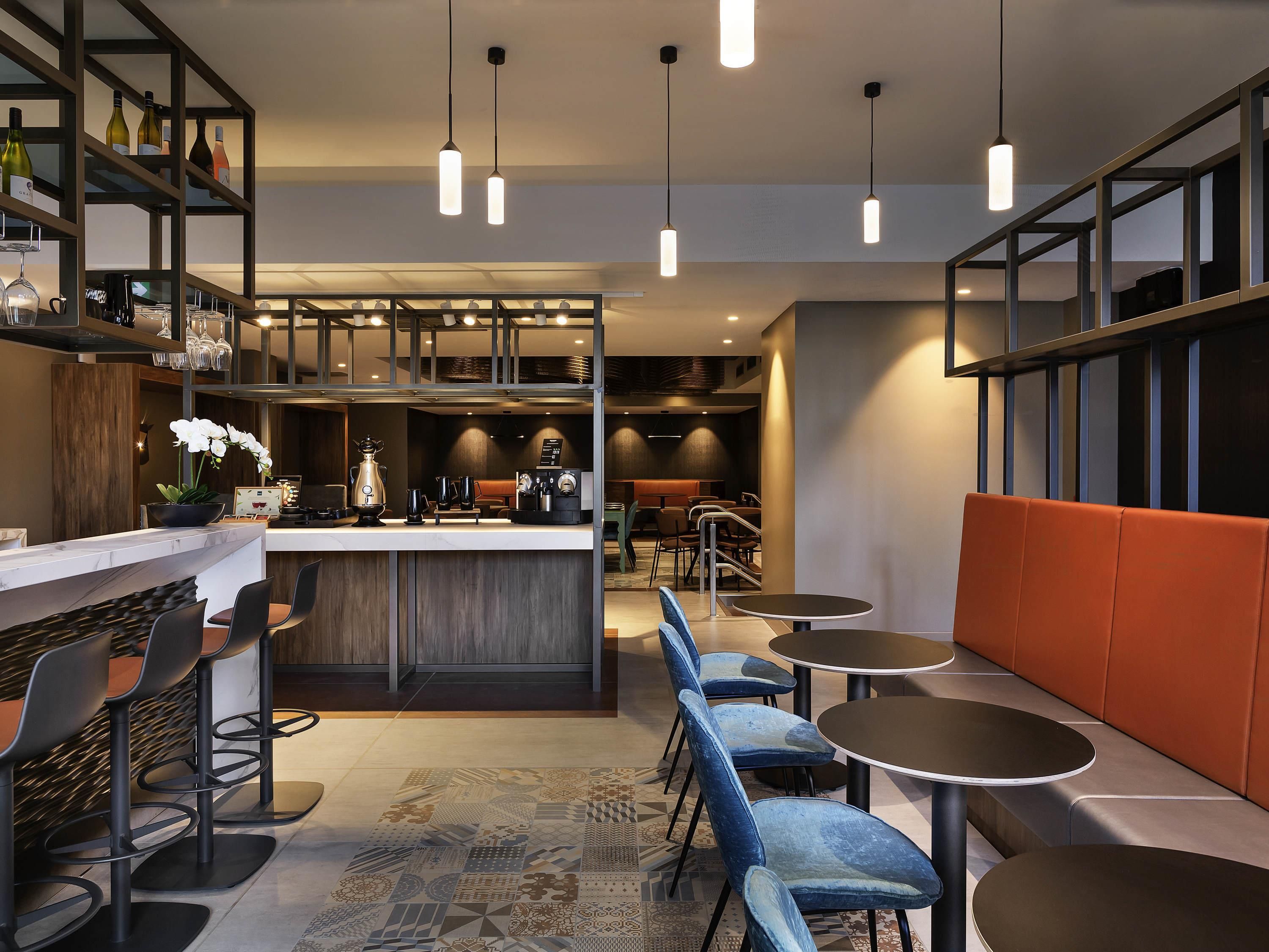 Un espacio moderno de bar con asientos, una barra y luminarias colgantes.