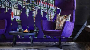 A modern lounge area with purple seating, a small table with a cup and a plate, and a decorative wall mural. - Mercure Auckland Queen Street (Auckland)
