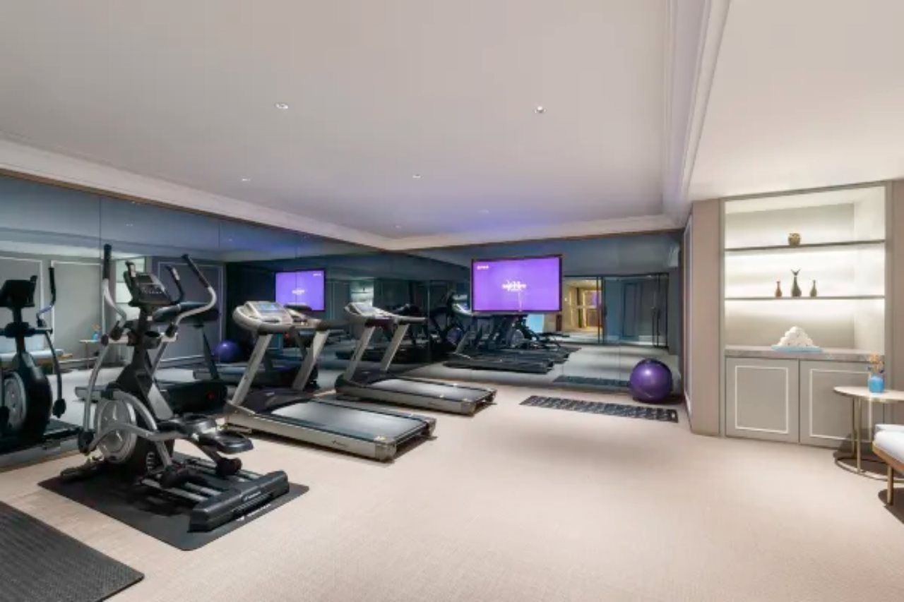 Un gimnasio moderno con cintas de correr, bicicletas estáticas y un espejo grande.