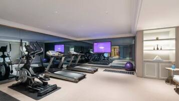 Un gimnasio moderno con cintas de correr, bicicletas estáticas y un espejo grande.