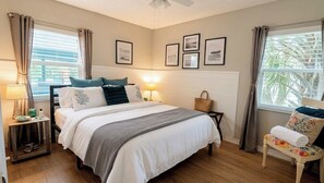 A hotel room with a bed, bedside tables, a chair, and a window with curtains.
