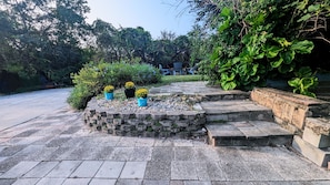 Una escalera de piedra que conduce a un jardín con flores amarillas en macetas y follaje verde.