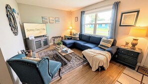 A cozy living room with a blue sofa, a coffee table, and a television.