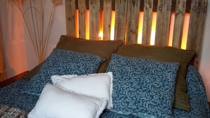 A bed with a wooden headboard, patterned bedding, and decorative pampas grass.
