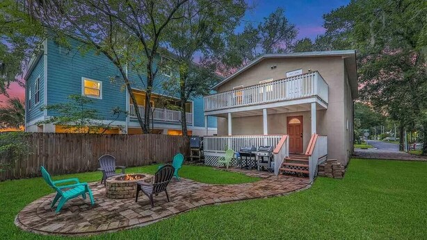 A two-story house with a backyard patio, a fire pit, and outdoor furniture.