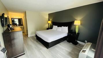 A hotel room with a bed, bedside lamps, a desk with a mirror, and a heater.