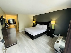 A hotel room with a bed, bedside lamps, a desk with a mirror, and a heater. - Rodeway Inn Silver Springs (Silver Springs)
