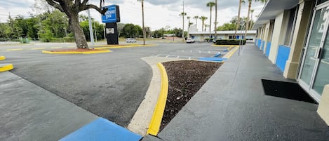 A parking lot with a blue and yellow curb, a sign for Wayfair Inn, and palm trees in the background.