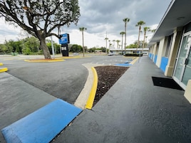 Un estacionamiento con bordillos azules y amarillos, un letrero del Wayfair Inn y palmeras al fondo.