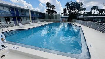 A swimming pool with lounge chairs and a building with a blue and white facade.