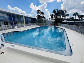A swimming pool with lounge chairs and a building with a blue and white facade. - Rodeway Inn Silver Springs (Silver Springs)