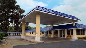 A motel with a covered parking area, a gas station, and a row of rooms. - Rodeway Inn Silver Springs (Silver Springs)