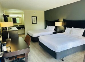 Een hotelkamer met twee bedden, een bureau, een stoel, een lamp en een klein tafeltje.
