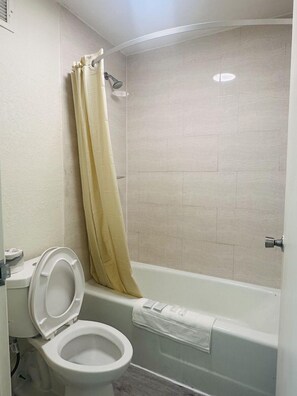 Een badkamer met toilet, douchegordijn en bad.