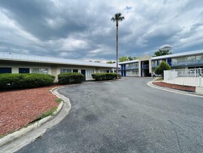 A motel with a parking lot, a palm tree, and a building with a blue and white facade. - Rodeway Inn Silver Springs (Silver Springs)