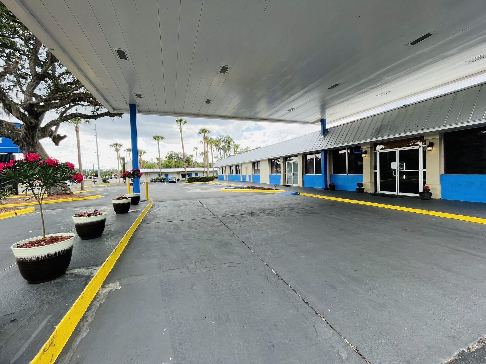 A gas station with a covered parking area, fuel pumps, and a building with large windows and a blue and white color scheme.