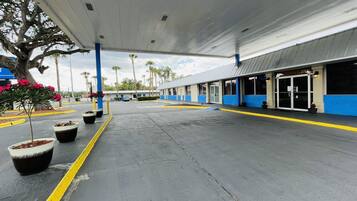 A gas station with a covered parking area, fuel pumps, and a building with large windows and a blue and white color scheme.