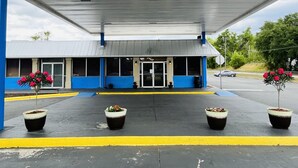 A gas station with a blue and white exterior, a covered entrance, and potted plants in front. - Rodeway Inn Silver Springs (Silver Springs)