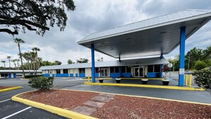 A gas station with a blue and white building, a covered parking area, and a parking lot with yellow curbs. - Rodeway Inn Silver Springs (Silver Springs)