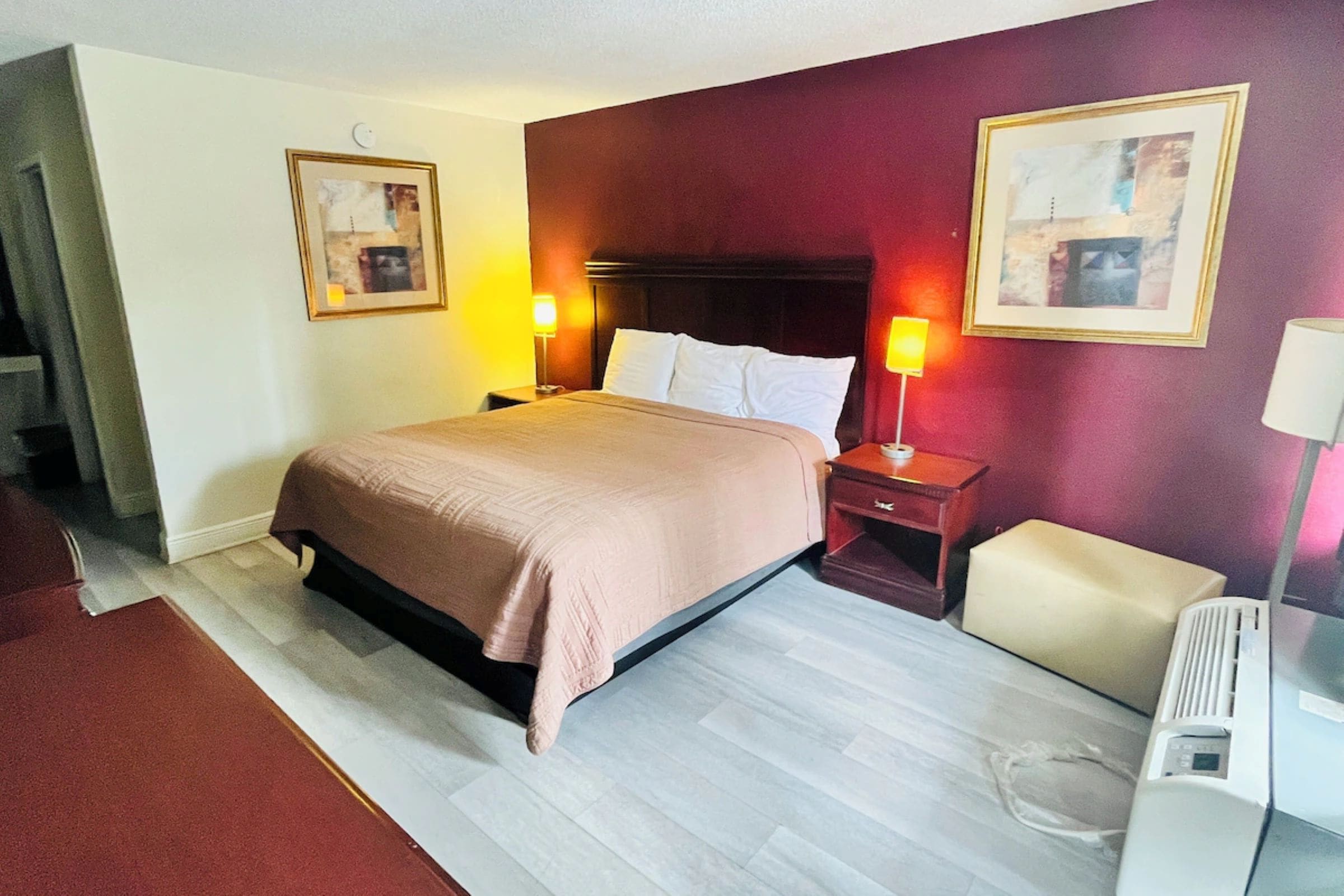 A hotel room with a bed, bedside tables, lamps, and two framed pictures on the walls.